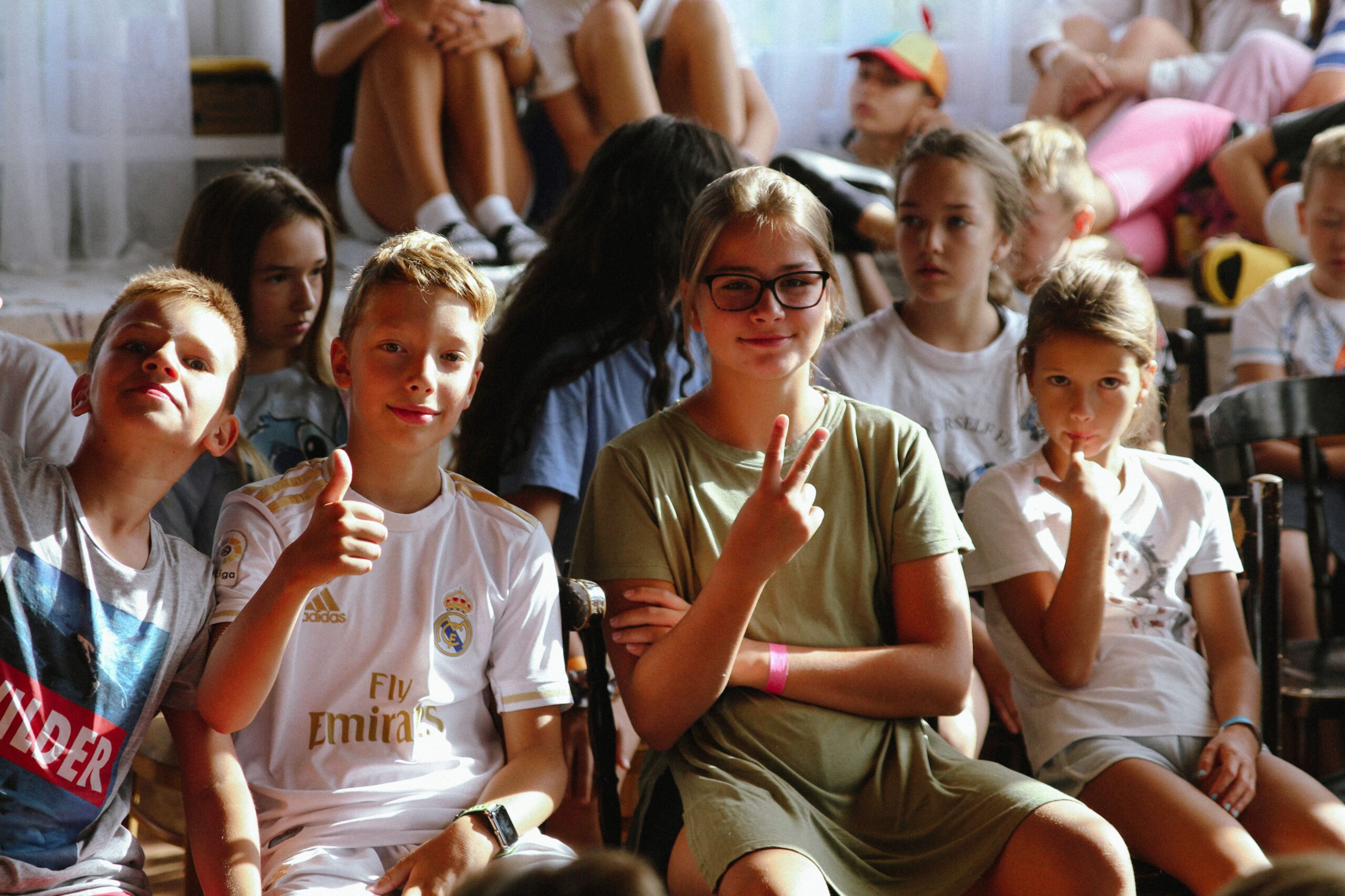 Cheerful group of children sitting together at an indoor event, showcasing friendships and diversity.
